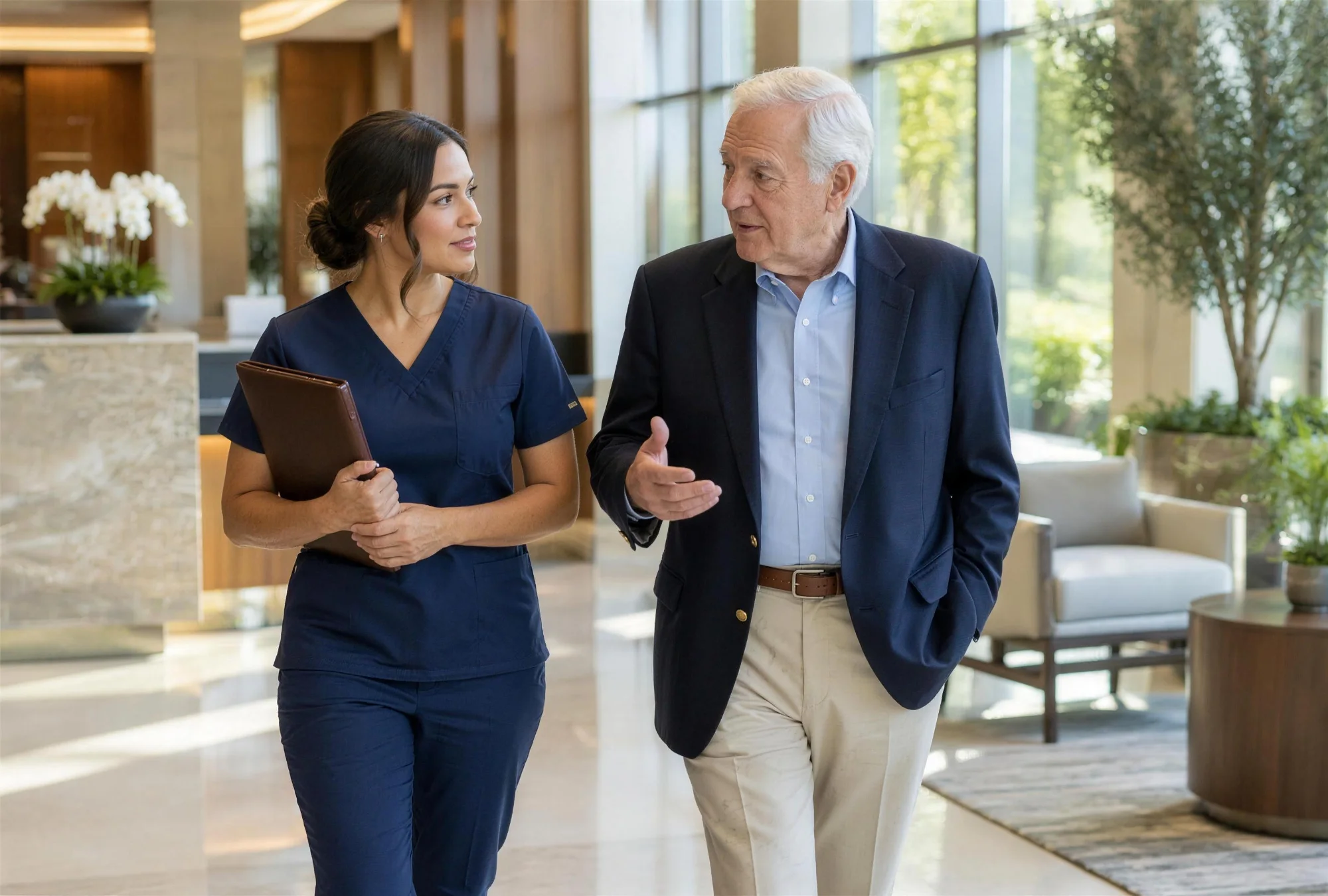 Certified nursing assistant with a leather folio walking beside an older gentleman through an elegant medical office lobby